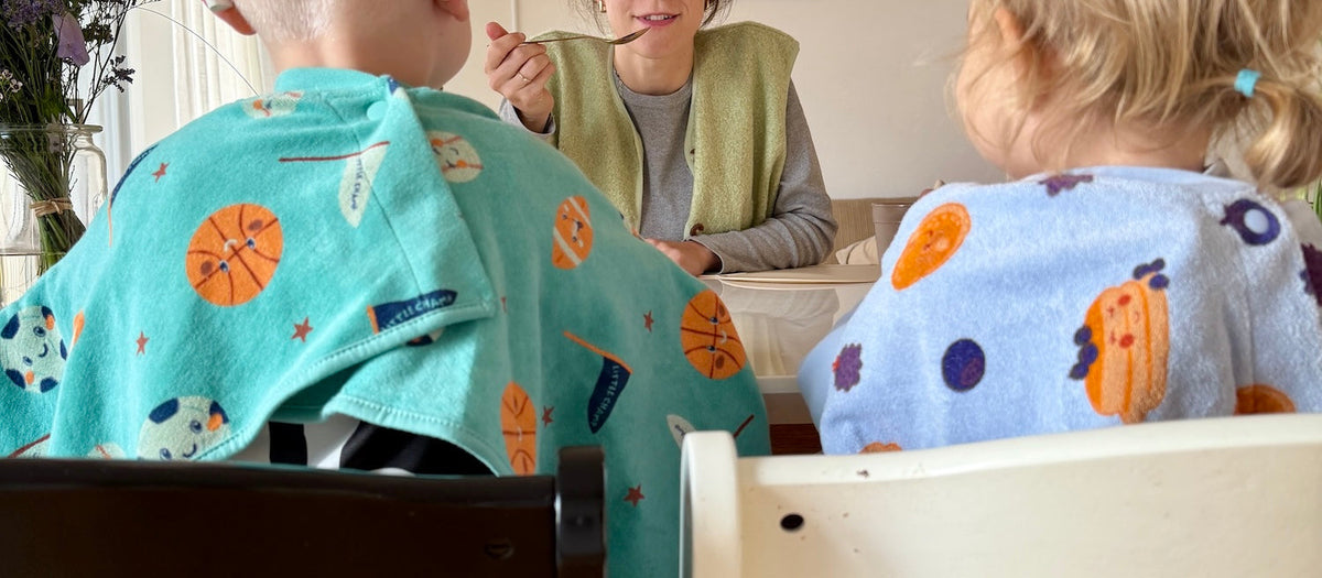 Zwei Kinder sitzen Elternteil gegenüber am Esstisch